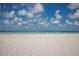 Expansive white sandy beach with clear turquoise water and a bright blue sky with fluffy white clouds at 5700 Gulf Shores Dr # B-137, Boca Grande, FL 33921