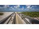 Scenic boardwalk leading to a pristine beach with clear skies, calm waters, and lush vegetation at 5700 Gulf Shores Dr # B-137, Boca Grande, FL 33921