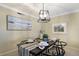 Dining room area featuring a modern chandelier, a black table setting for four, and neutral walls at 5700 Gulf Shores Dr # B-137, Boca Grande, FL 33921