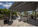 Outdoor patio area with a shaded pergola, dining table, chairs, and multiple grills for outdoor cooking at 5700 Gulf Shores Dr # B-137, Boca Grande, FL 33921