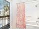 Bright bathroom featuring a tub/shower with a coral-patterned curtain and an adjacent outdoor deck at 6430 Manasota Key Rd, Englewood, FL 34223