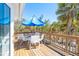 Outdoor deck with a blue umbrella, a white table and chairs with a serene tropical landscape at 6430 Manasota Key Rd, Englewood, FL 34223