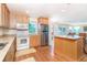The well-lit kitchen includes stainless steel refrigerator, microwave, white oven, island and hardwood floors at 6430 Manasota Key Rd, Englewood, FL 34223