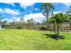 Well-manicured lawn and landscaping, featuring a young palm tree and a wooded backdrop at 8952 Scallop Way, Placida, FL 33946