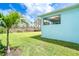 Expansive backyard view showcasing the home's exterior and a young palm tree in the landscaping at 8952 Scallop Way, Placida, FL 33946
