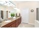 Bathroom featuring dual sinks, granite countertop, wood cabinets, large mirror, and decorative accents at 8952 Scallop Way, Placida, FL 33946