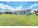 Back exterior showcasing the screen patio, lush lawn, and well-maintained landscaping at 8952 Scallop Way, Placida, FL 33946