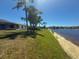 Lush backyard featuring a pristine lakefront view and sandy beach, creating a tranquil escape at 9064 Bantry Bay Blvd, Englewood, FL 34224