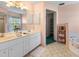 Bathroom featuring a double sink vanity, tiled floors, and a separate tub at 9064 Bantry Bay Blvd, Englewood, FL 34224