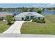 Beautiful single-story home with a well-manicured lawn and a serene water view in the background at 9064 Bantry Bay Blvd, Englewood, FL 34224