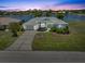 Scenic view of a home on the water at sunset, with a lush lawn and a driveway leading to an attached garage at 9064 Bantry Bay Blvd, Englewood, FL 34224