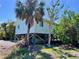 Raised beach house on stilts, surrounded by lush tropical vegetation under a clear blue sky at 9270 Little Gasparilla Is, Placida, FL 33946