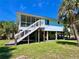 Inviting raised beach house with a screened porch and stairs under blue sky at 9270 Little Gasparilla Is, Placida, FL 33946