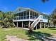 Inviting raised beach house with a screened porch and a well-maintained lawn under a bright blue sky at 9270 Little Gasparilla Is, Placida, FL 33946