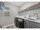 Well-organized laundry room with sink, dark washer and dryer, and a window letting in natural light at 9532 Miami Cir, Port Charlotte, FL 33981