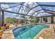 Relaxing view of screened-in pool with brick paver deck, canal view, and tropical landscaping at 9532 Miami Cir, Port Charlotte, FL 33981