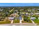 Expansive aerial view showcasing a single-story home nestled in a lush, green neighborhood with mature trees and landscaping at 9869 Gulfstream Blvd, Englewood, FL 34224