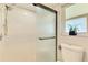 Updated bathroom with a glass shower door, tiled walls, and a decorative plant in the window at 9869 Gulfstream Blvd, Englewood, FL 34224