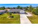 Charming one-story home featuring a long driveway, a well-manicured lawn and a tropical tree at 9869 Gulfstream Blvd, Englewood, FL 34224