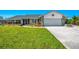 Charming single story home featuring a manicured lawn and garden beds and a garage at 9869 Gulfstream Blvd, Englewood, FL 34224