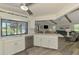 Open kitchen with stainless steel appliances, island, and connection to the living room and outdoor pool area at 9869 Gulfstream Blvd, Englewood, FL 34224