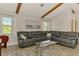 Bright living room featuring a dark gray leather couch, vaulted ceilings, and beautiful wood beams at 9869 Gulfstream Blvd, Englewood, FL 34224