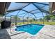 Inviting screened-in pool with clear blue water, gray brick pavers, and grill for a backyard oasis at 9869 Gulfstream Blvd, Englewood, FL 34224