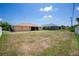 Spacious backyard with a view of a screened lanai and neighboring homes on a sunny day at 10116 Melanie Ave, Englewood, FL 34224