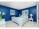 Charming bedroom with blue walls, white furniture, and two bright windows at 10116 Melanie Ave, Englewood, FL 34224