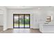 A view of the living room showing the large glass door and the kitchen with white cabinets at 10242 Hallendale Dr, Port Charlotte, FL 33981
