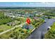 Aerial view of a canal front home with a pool in a scenic neighborhood with lush landscaping and a red pin marker at 10454 Atenia St, Port Charlotte, FL 33981