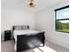 Cozy bedroom with a black sleigh bed, nightstand, stylish chandelier, and natural light at 10454 Atenia St, Port Charlotte, FL 33981