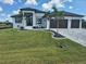 Well-manicured lawn of a home featuring a three-car garage, dark trim windows, and decorative palm trees at 10454 Atenia St, Port Charlotte, FL 33981