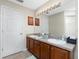 Bathroom featuring double sinks, ample lighting, wood cabinets and a large vanity mirror at 1247 Nora Ln, North Port, FL 34286
