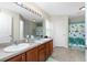 Bathroom featuring double sinks, wood cabinets and a shower/tub combination with a door nearby at 1247 Nora Ln, North Port, FL 34286