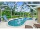 Relaxing screened-in pool area with clear blue water, lounge chairs, and lush greenery at 1247 Nora Ln, North Port, FL 34286