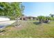 Charming single-story home featuring mature trees, a well-manicured lawn, and blooming flower beds at 13080 Proctor Ave, Port Charlotte, FL 33981