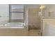 Bright bathroom featuring a soaking tub next to a glass-enclosed shower with neutral toned tile at 13282 Scrub Jay Ct, Port Charlotte, FL 33953