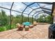 This screened-in patio features brick pavers, cozy wicker furniture, and a beautiful backyard view at 13282 Scrub Jay Ct, Port Charlotte, FL 33953