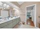 Bright bathroom with double sink, large mirror, and decor; bedroom is visible through doorway at 13703 Drysdale Ave, Port Charlotte, FL 33981