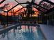 Sparkling pool with a colorful sunset view from the screened-in lanai at 13703 Drysdale Ave, Port Charlotte, FL 33981