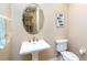 Half bath features pedestal sink, oval mirror, and decorative ocean artwork at 1375 Beach Rd # 201, Englewood, FL 34223