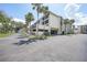 Condominium building with palm trees and a parking area on a sunny day at 1501 Beach Rd # 310, Englewood, FL 34223