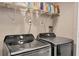 Well-equipped laundry room features gray washer and dryer and shelving for storage at 1730 Manasota Beach Rd # 204, Englewood, FL 34223