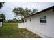 Home exterior showing the side yard with a white fence, gravel, and green grass at 21 Sportsman Way, Rotonda West, FL 33947