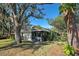 Back exterior view of house, mature trees and shrubs, screen porch, with pond nearby at 232 Southampton Ln # 259, Venice, FL 34293