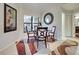 Cozy dining area with a glass table, four chairs, and a decorative mirror, next to a window and doorway at 232 Southampton Ln # 259, Venice, FL 34293