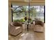 Bright sunroom featuring two chairs and picturesque views of a serene lake surrounded by lush trees at 232 Southampton Ln # 259, Venice, FL 34293