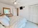 Bright bedroom features a ceiling fan, TV, closet, and dresser with decorative mirror at 2380 N Beach Rd # 210, Englewood, FL 34223