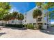 Exterior shot of the building featuring multiple balconies, lush trees, and a parking area at 2380 N Beach Rd # 210, Englewood, FL 34223